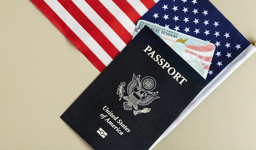 U.S. passport and Green Card on an American flag, symbolizing immigration success stories from H-1B extension to citizenship through an EB5 investment.