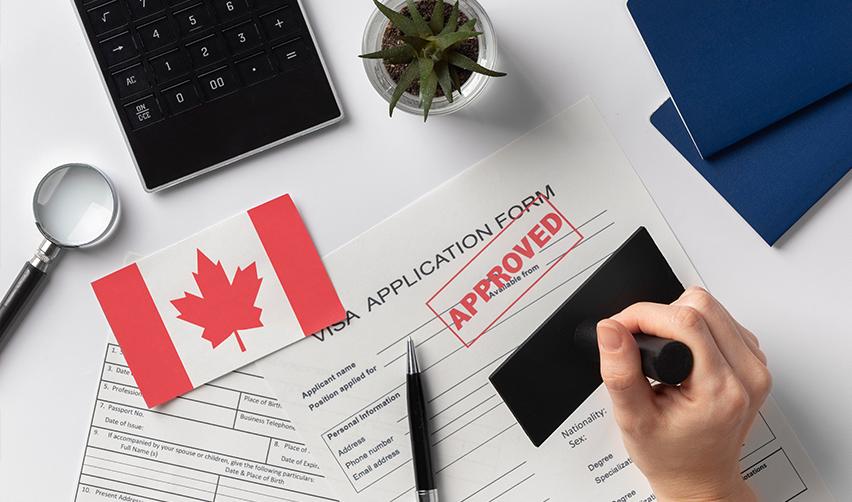 Approved visa application form with a Canadian flag, pen, and passport, illustrating the successful path to a U.S. Green Card for Canadian investors.