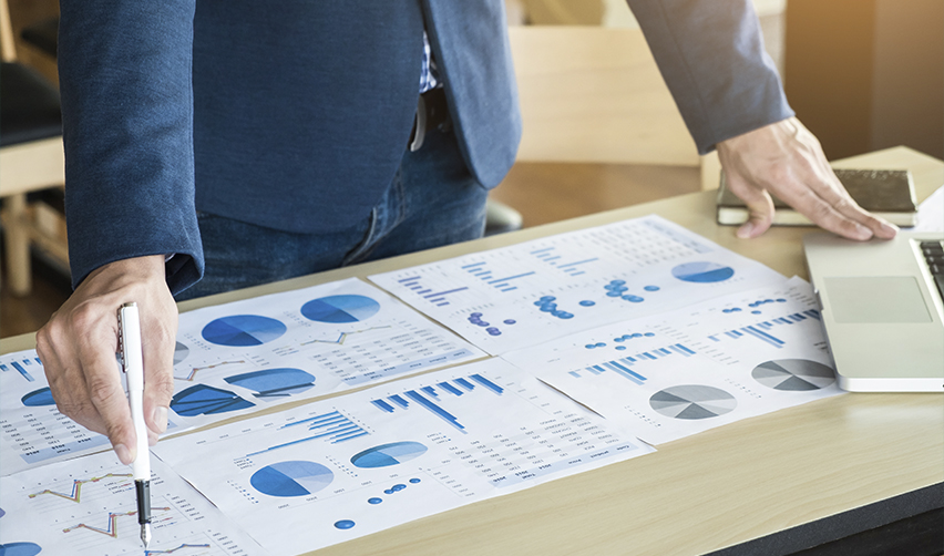 Professional analyzing financial graphs on a desk, preparing EB5 regional center project investment strategy and assessing job creation potential in targeted employment areas.