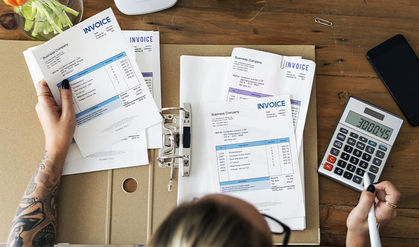 Close-up of invoices and a calculator on a desk, symbolizing the financial record-keeping required for EB5 source and path of funds documentation.