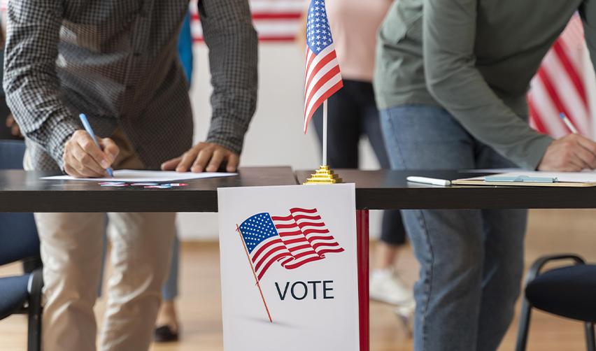 Citizens casting ballots at a voting booth with American flags, highlighting the right to vote granted by American citizenship.