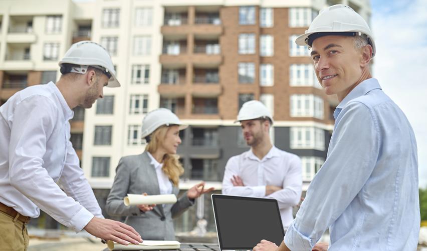 Construction team wearing hard hats discussing plans at a residential development site, symbolizing collaborative efforts at Kolter Homes and EB5AN projects.