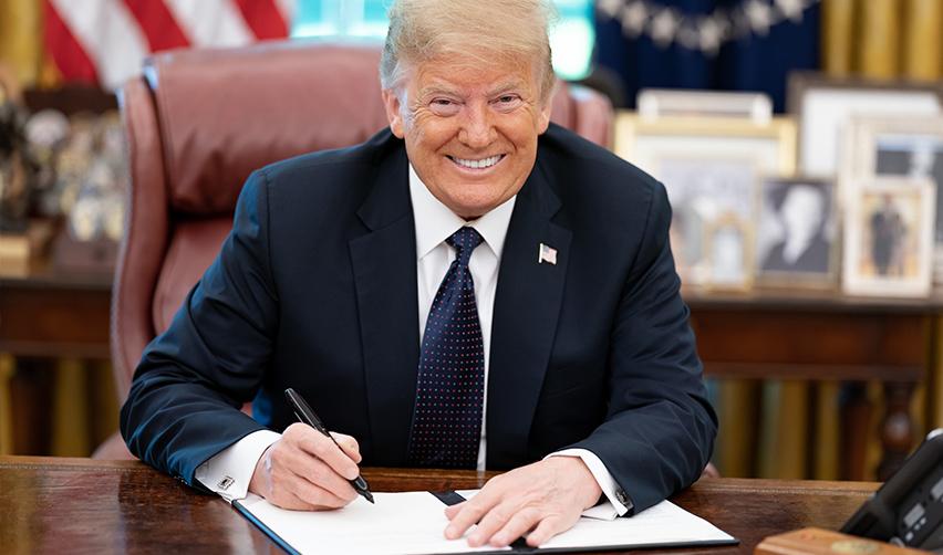 An image of President Donald Trump while signing an executive order, potentially about the gold card proposition, symbolizing potential changes the trump administration might make that would affect immigrant investors.