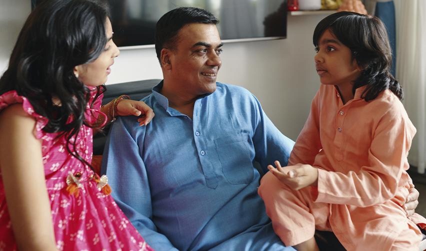 A father in traditional attire talking with his two children, representing EB5 visa applicants planning U.S. residency as a family.