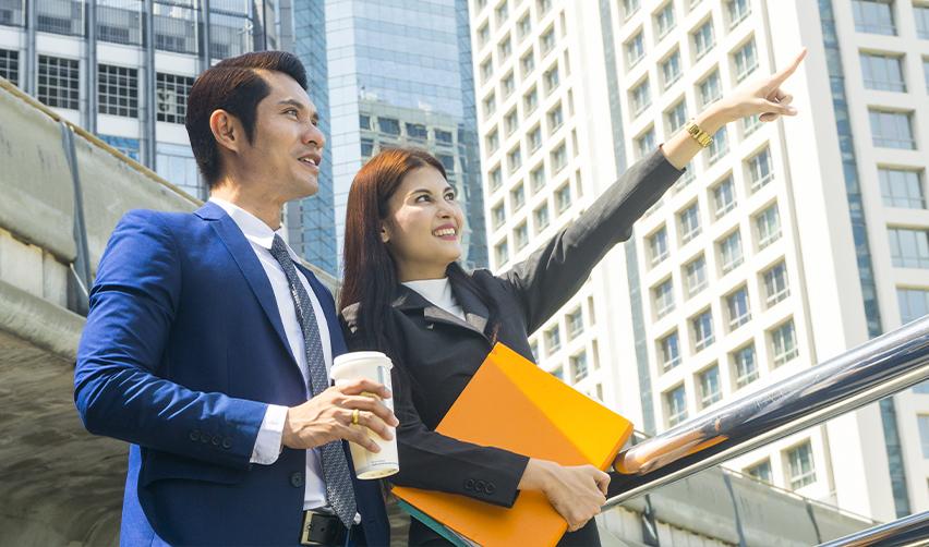 Two business professionals discussing investment opportunities in front of a modern city skyline, representing global EB5 investors exploring U.S. residency options.