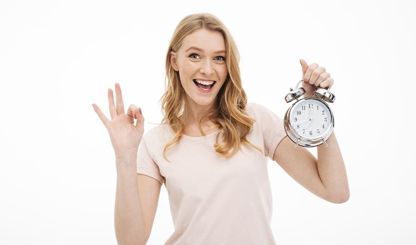 Smiling woman holding a clock, signifying the streamlined and faster EB5 processing timelines available through EB5AN projects.