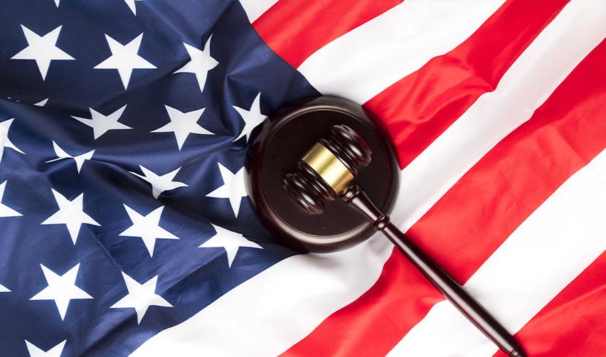 Judge’s gavel resting on an American flag, symbolizing legal protections and responsibilities of U.S. residents and citizens.