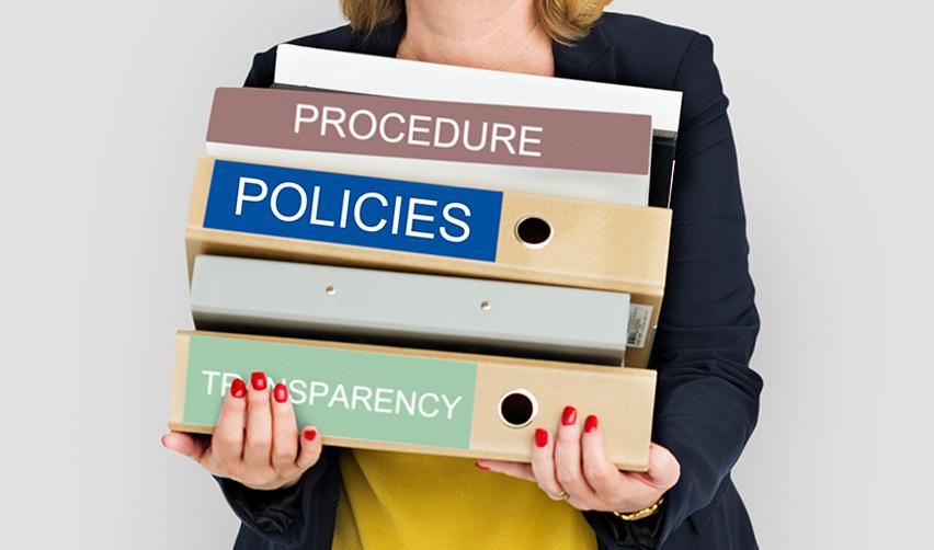 A stack of folders labeled with policies and transparency reflects the complex procedures behind the introduction of a gold card, immigration enforcement and regional centers due diligence.