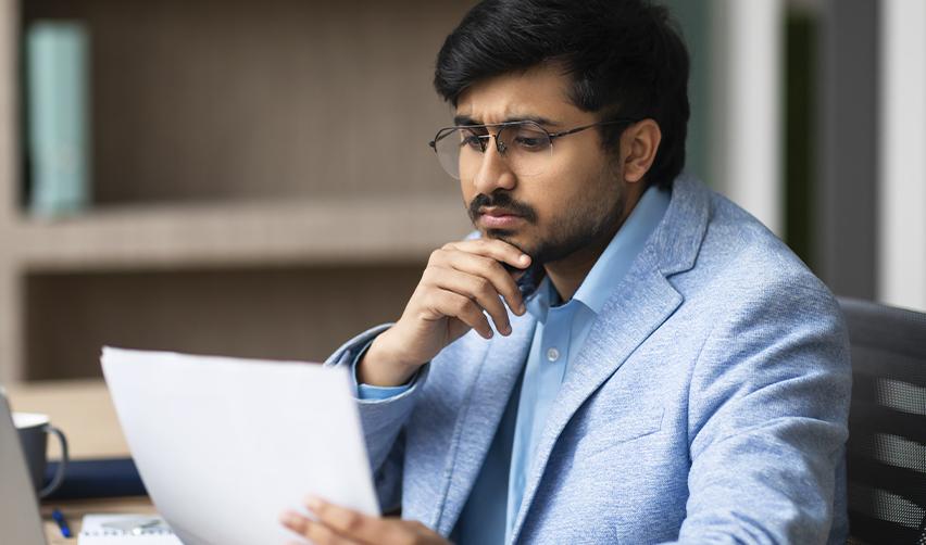Thoughtful Indian investor analyzing rural EB5 project documents and immigration timelines, reflecting strategic decision-making amid urban visa backlogs.