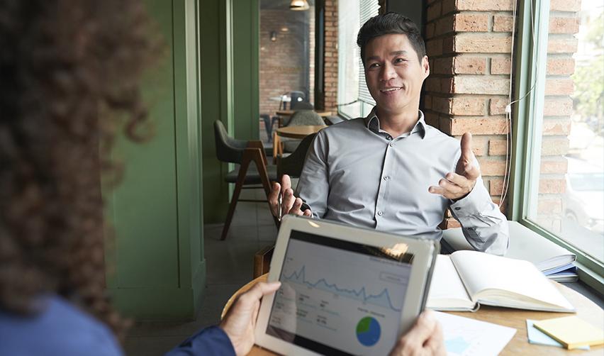 Immigration advisor discussing EB5 rural investment strategy with a client, using data visualizations and approval trends on a tablet.