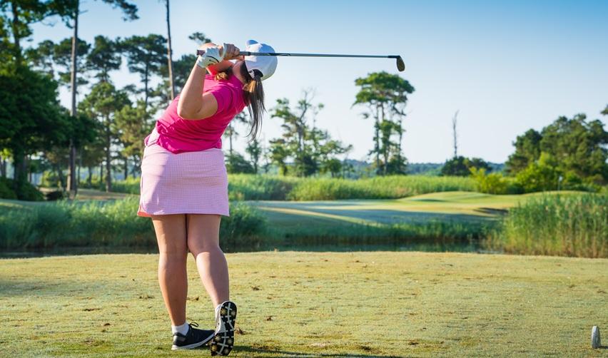 A person swinging a golf club in the large golf court at Bay Creek resort.