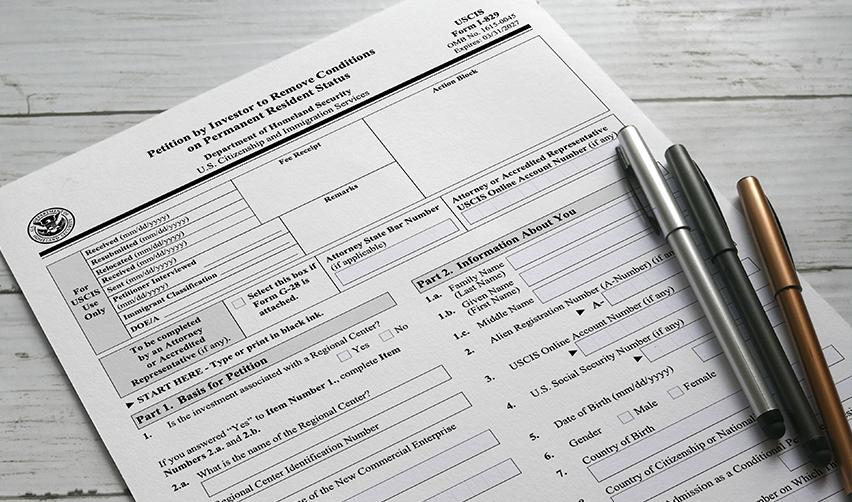 USCIS Form I-829 Petition by Investor to Remove Conditions, shown with pens on a wooden desk, marking the final stage of the EB5 Green Card process.