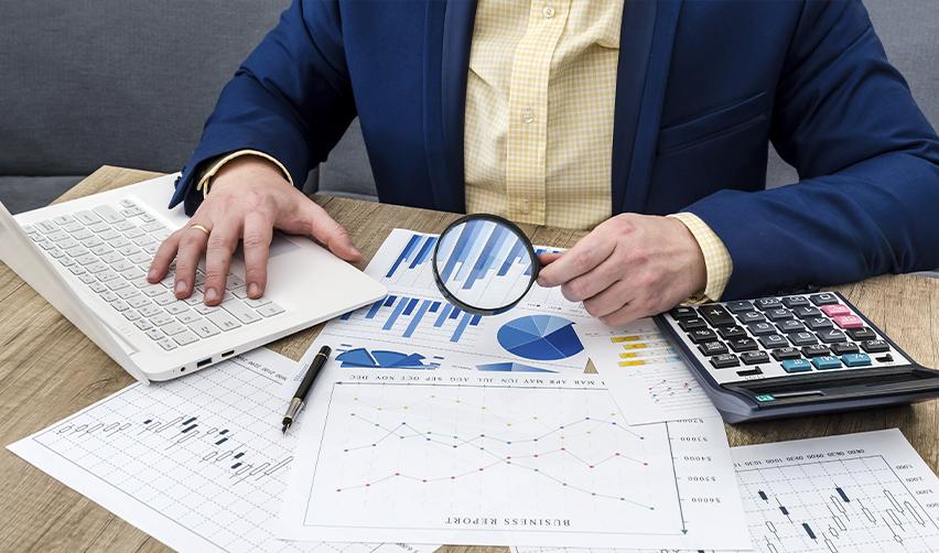 Businessman examining investment data with magnifying glass, illustrating EB5 investor due diligence in evaluating job-creating entities and financial risk.