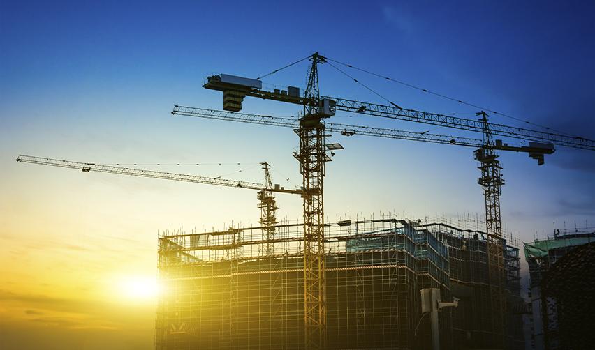 Construction cranes above a building site during sunset, illustrating project visibility and real-time progress updates in EB5 development projects.