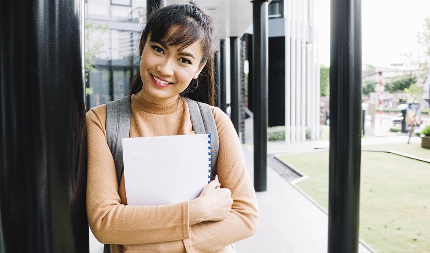 A female student standing on a U.S. university campus, highlighting the educational benefits of EB5 residency for children of investors.