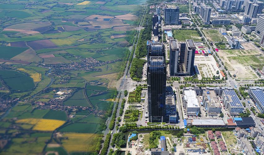 Aerial view showing rural farmland next to urban skyscrapers, highlighting the contrast between EB5 rural and urban new commercial enterprise locations.