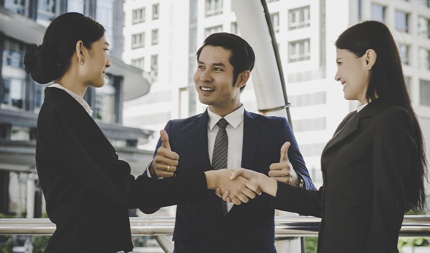 EB5 investors and regional center representative shaking hands with approval gesture, highlighting successful collaboration.