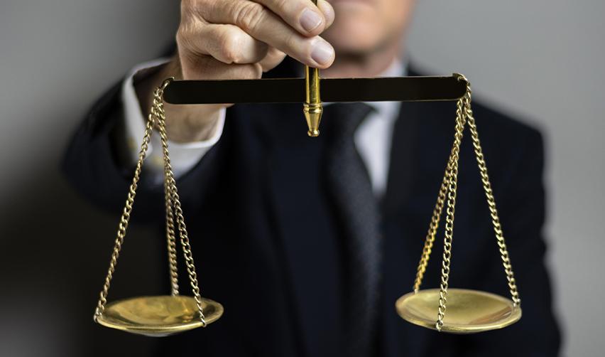 A businessman in a suit holding balanced scales, representing regulatory compliance and fairness in EB5 investment and redeployment rules.