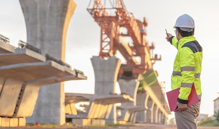Construction worker in high-visibility gear overseeing a large-scale EB5 project, illustrating rural TEA investments.