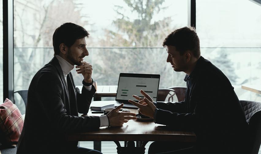 An investor and a regional center team member engage in a serious discussion over a laptop, representing expert legal or financial consultation for EB5 investors.