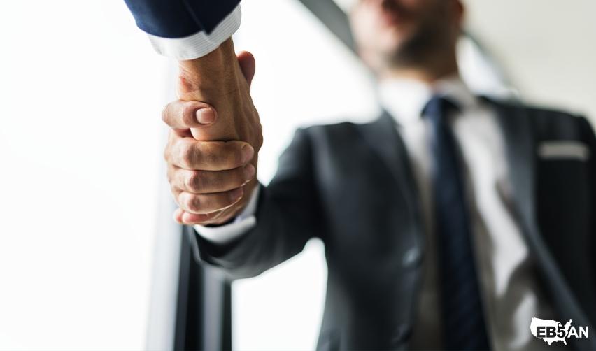 Close-up of a handshake between two suited professionals next to the EB5AN logo, emphasizing accountability, transparency, and mutual trust in the EB5 investment process.