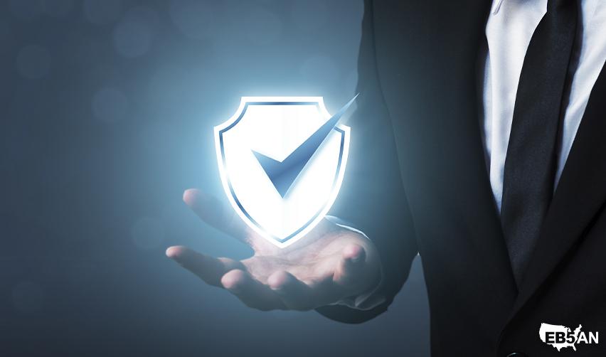 A businessman holding a glowing digital shield with a checkmark, representing secure EB5 investments, fund protection, and project transparency by EB5AN.