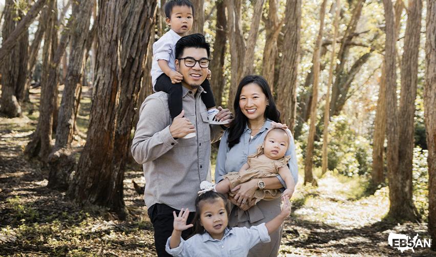 Smiling immigrant family with children in a wooded rural setting, highlighting the lifestyle and Green Card benefits of EB5 rural investments as opposed to making a capital investment in urban tea projects.