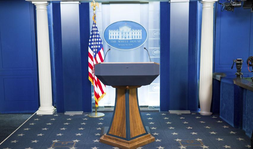 A podium at the White House press briefing room with an American flag, where major shifts in immigration law are announced and clarified for the public.