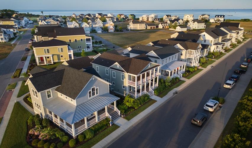 Aerial view of Bay Creek neighborhood with rows of modern coastal homes and the Chesapeake Bay in the background, underscoring residential growth and EB5 project success.