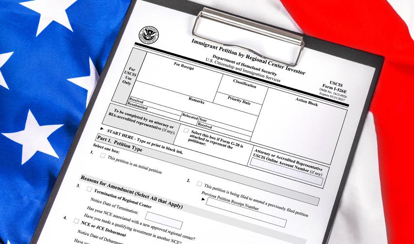 USCIS Form I-526E on a clipboard with the American flag, representing EB5 immigration petitions and the path to U.S. residency through Bay Creek.