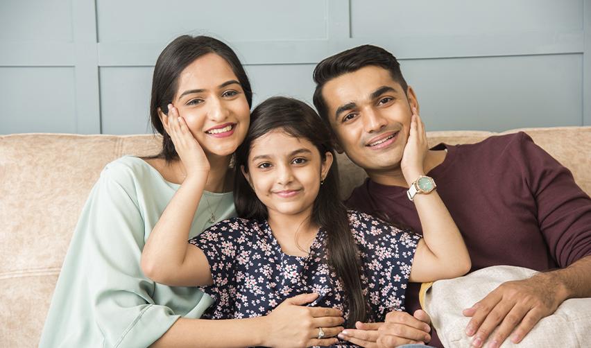 Happy Indian family sitting together at home, reflecting the security and family Green Card benefits of the EB5 immigrant investor program.