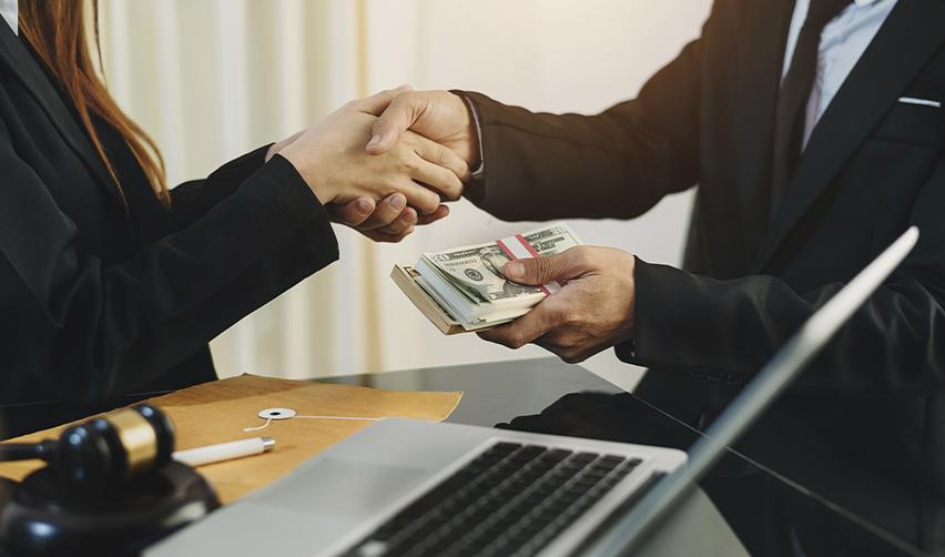 Businesspeople shaking hands while exchanging U.S. dollars, illustrating successful EB5 loan repayment and secure investment outcomes.