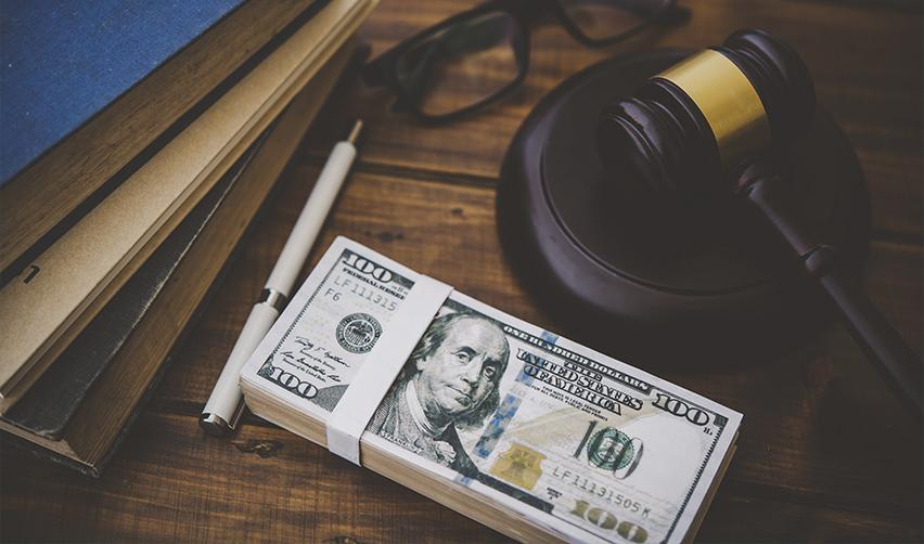 Stack of $100 bills beside a gavel, legal books, and a pen, representing EB5 loan agreements and source of funds documentation.