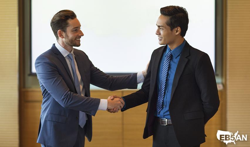 Two professionals shaking hands in a meeting room, symbolizing investor confidence in EB5AN regional centers and successful capital recovery.
