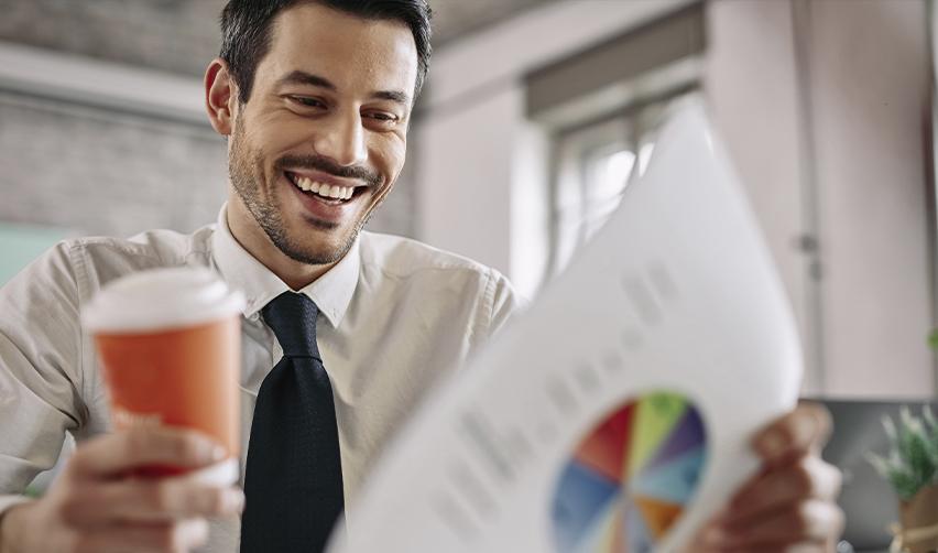 Smiling professional reviewing a colorful financial chart, reflecting investor confidence and positive EB5 project performance reports.