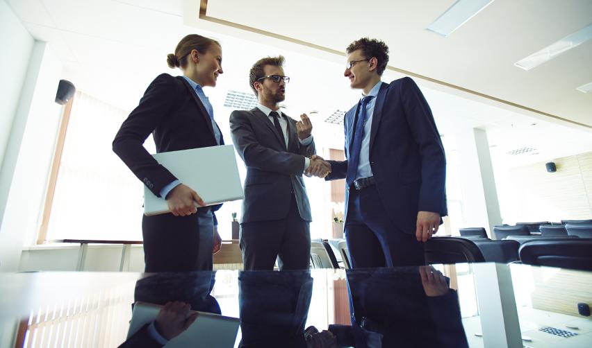 Business professionals shaking hands during a meeting, symbolizing EB5 investor protections, senior loan agreements, and trusted partnerships at EB5AN.