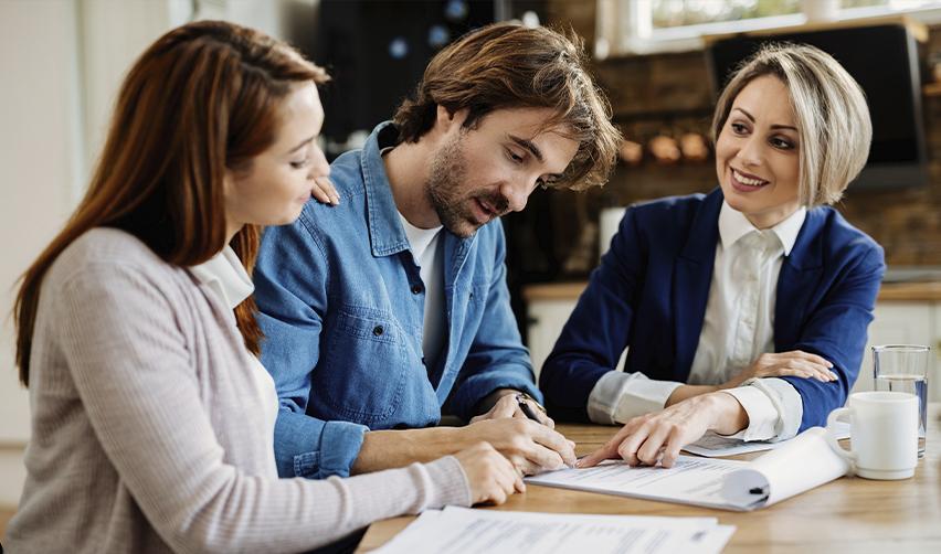 Couple reviewing and signing financial documents with a professional advisor, depicting EB5 loan structuring and documentation process.