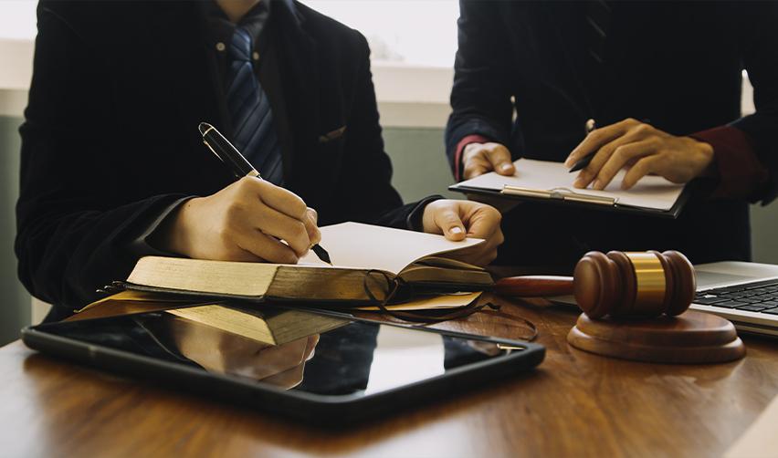 Close-up of lawyers drafting agreements with a gavel and legal books on the table, illustrating the role of immigration and securities counsel in EB5 transactions.
