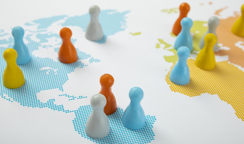 Colorful game pieces placed across a world map representing EB5 investors from diverse countries applying for U.S. Green Cards.