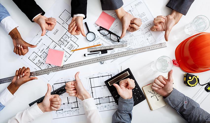 A group of people gathered around construction blueprints giving thumbs up and down, illustrating EB5 project progress reviews and investor transparency through regular updates.