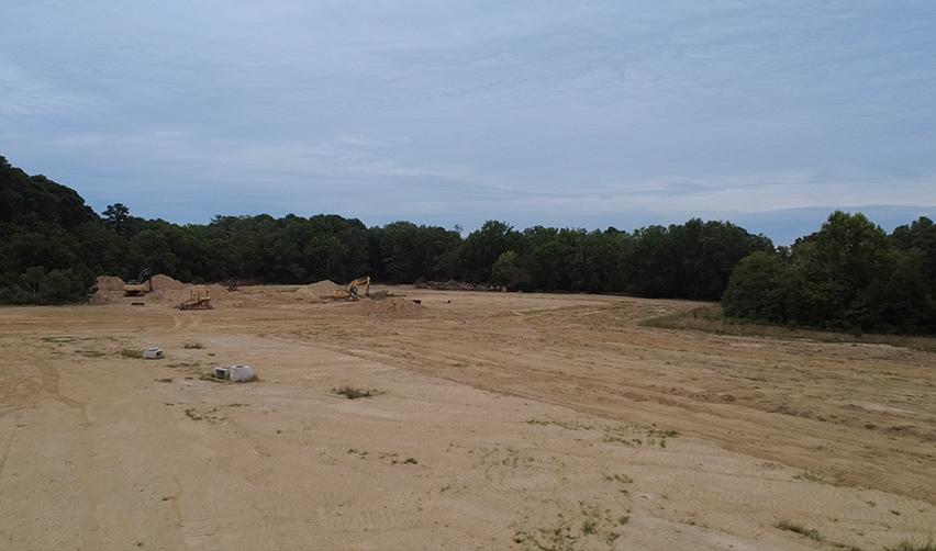 Wide view of cleared land at Bay Creek with construction machinery preparing new residential areas for EB5 project expansion.