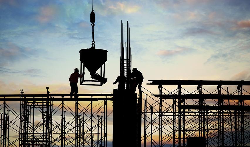 Construction workers on scaffolding at sunset, symbolizing job creation and development progress supported by EB5 investment funds.