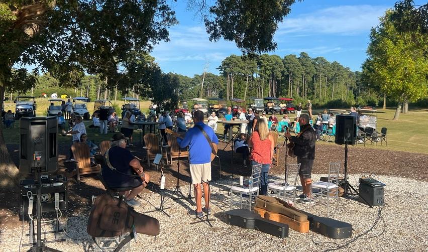 Bay Creek residents enjoying Friday Live with live music, outdoor seating, and golf carts gathered in a relaxed community setting.