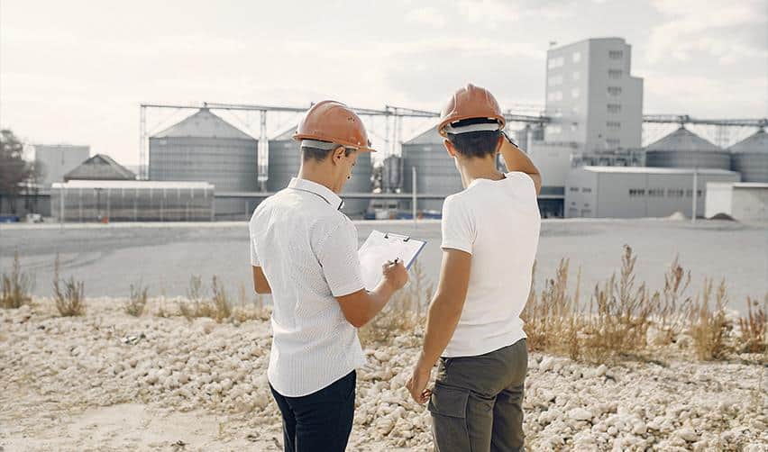 Two construction workers in hard hats reviewing plans at an urban site, illustrating why EB5 rural projects are the best choice.