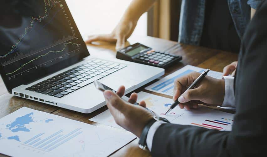 Financial advisors analyzing charts and project data on a laptop, reflecting EB5 investors evaluating capital structure and return projections.