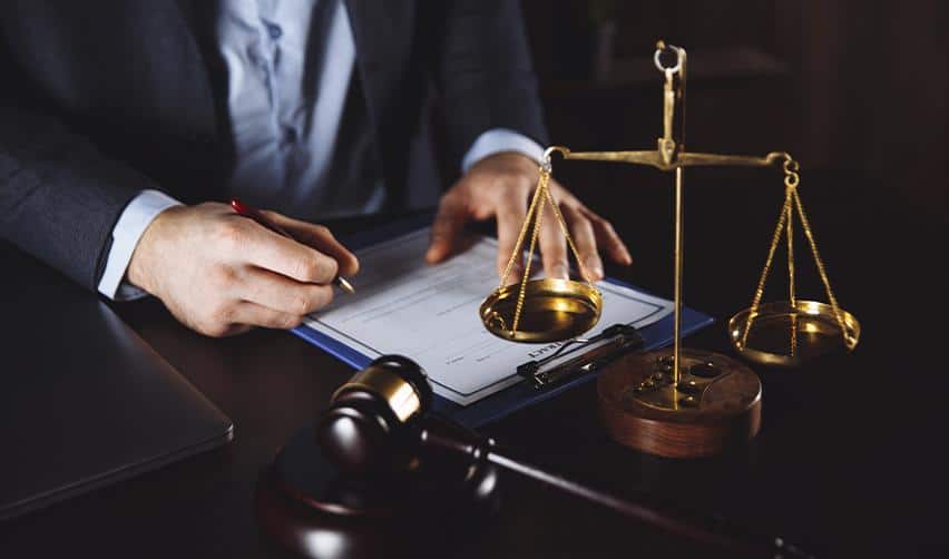 An EB5 immigration attorney reviewing legal documents beside scales of justice, symbolizing expertise and due diligence in the EB5 process.