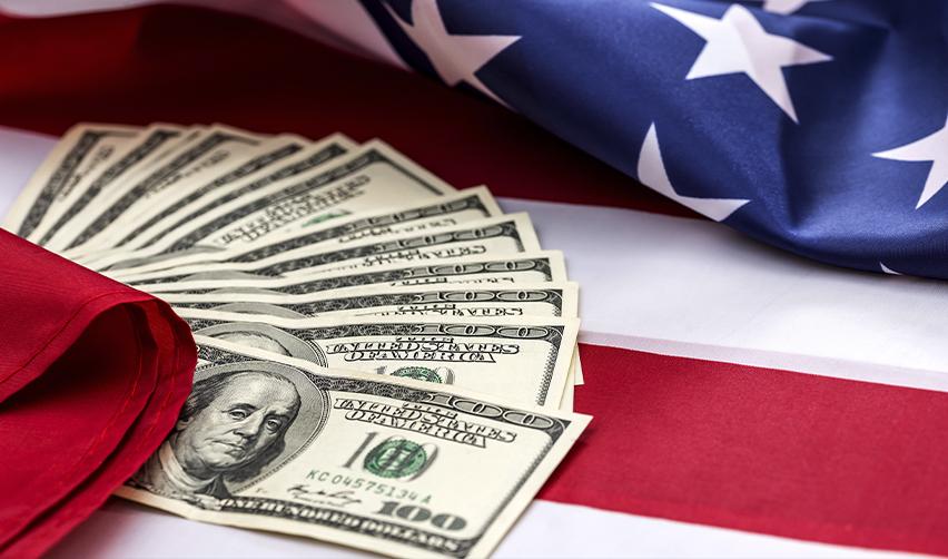 Stack of hundred-dollar bills spread across an American flag, illustrating EB5 investment funds supporting U.S. economic growth and Green Card opportunities.