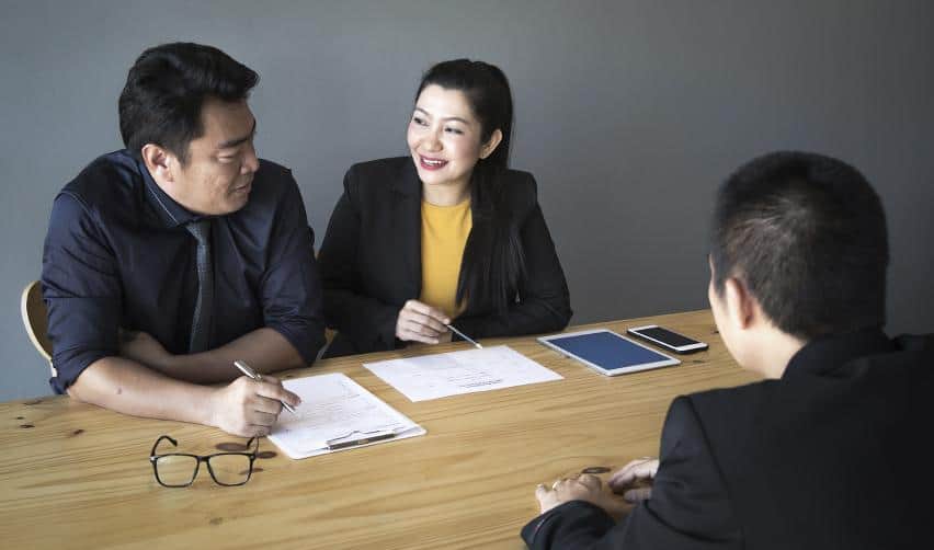 A group of professionals discussing EB5 investment documents in an office, highlighting collaboration between investors and regional center representatives.