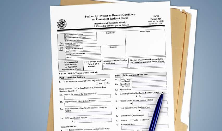 A stack of USCIS Form I-829 petitions with a pen on top, representing EB5 investors filing to remove conditions on their Green Cards.