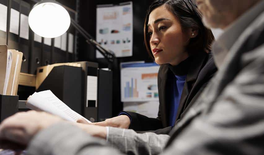 Two professionals reviewing documents together in an office, representing the human due diligence that pairs with AI-driven EB5 project evaluation.